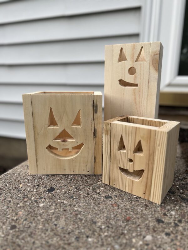 set of three unlit, unfinished wooden jack-o-lantern fall decor luminaries on a front step