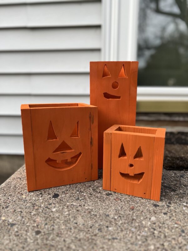 set of three unlit wooden jack-o-lantern fall decor luminaries painted orange on a front step