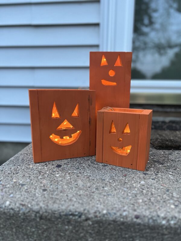 set of three wooden jack-o-lantern fall decor luminaries painted orange with a glowing light inside