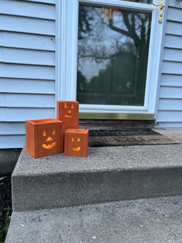 set of three wooden jack-o-lantern fall decor luminaries painted orange with a glowing light inside