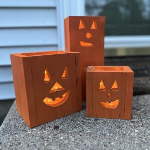 set of three wooden jack-o-lantern fall decor luminaries painted orange with a glowing light inside