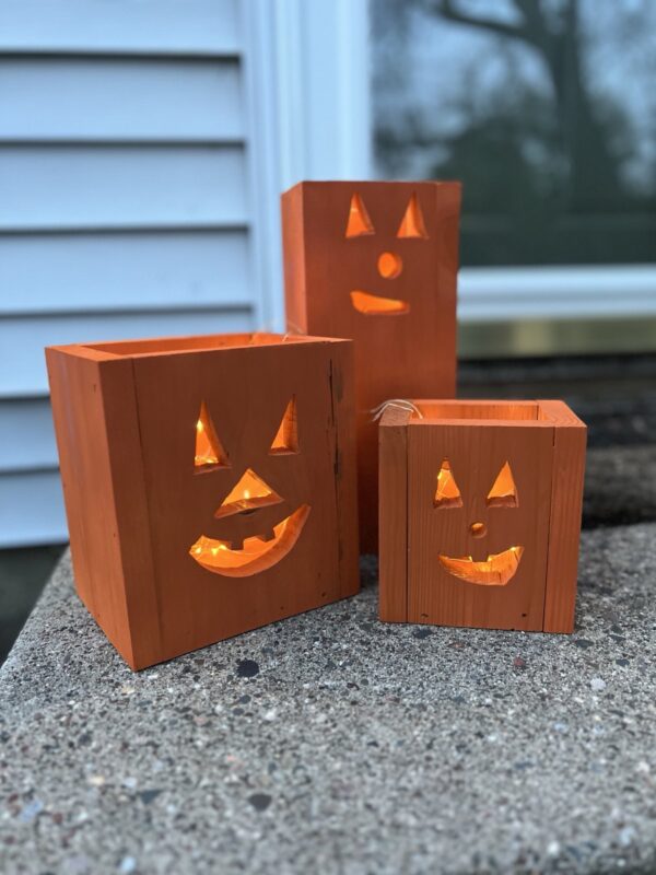 set of three wooden jack-o-lantern fall decor luminaries painted orange with a glowing light inside