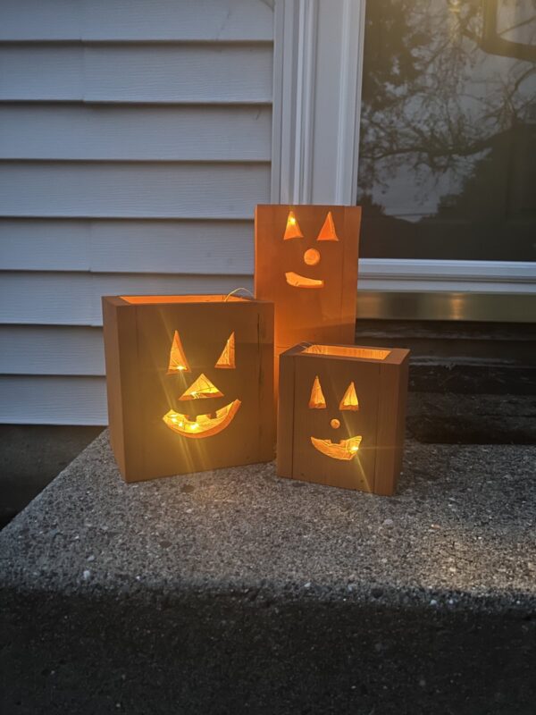 set of three wooden jack-o-lantern fall decor luminaries painted orange with a glowing light inside